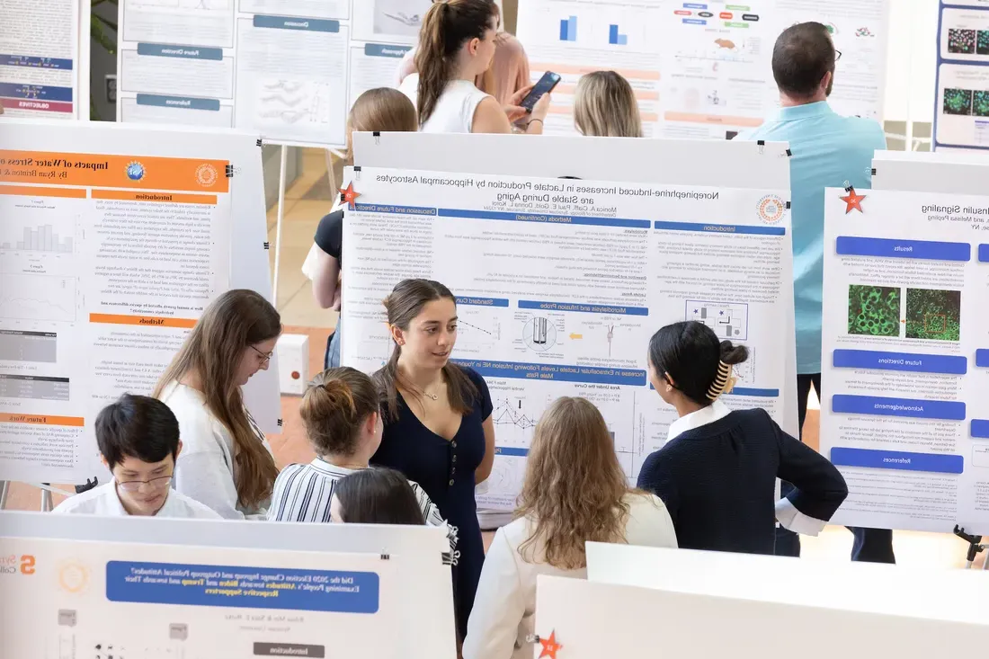 Students standing and smiling at a research symposium.